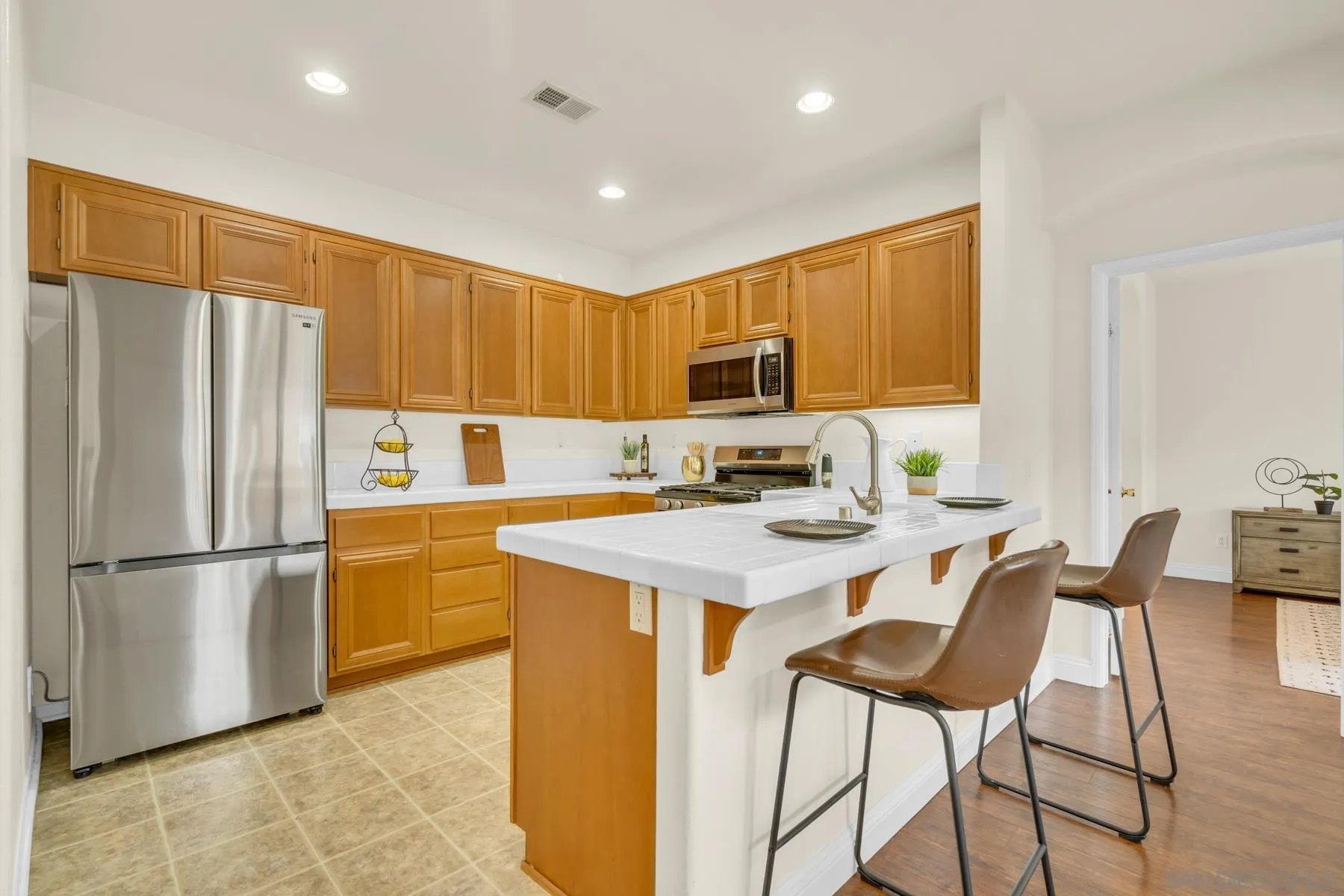 649 Sumner Way, Unit 6 Oceanside, CA 92058 - Photo 4 of 30 a kitchen with a refrigerator a microwave a sink and chairs