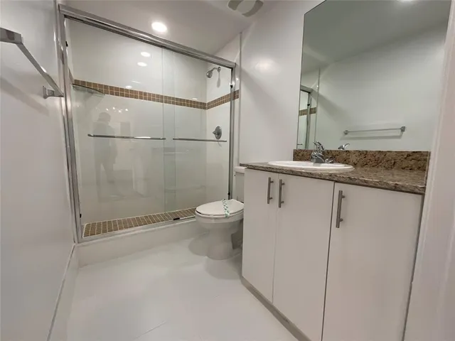 a bathroom with a granite countertop sink mirror and toilet