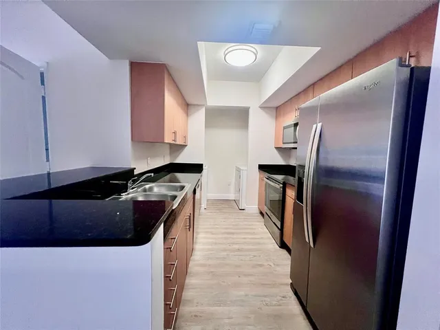 a kitchen with stainless steel appliances granite countertop a refrigerator a sink and wooden cabinets