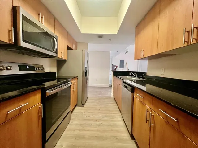 a kitchen with stainless steel appliances granite countertop a stove a sink and a microwave