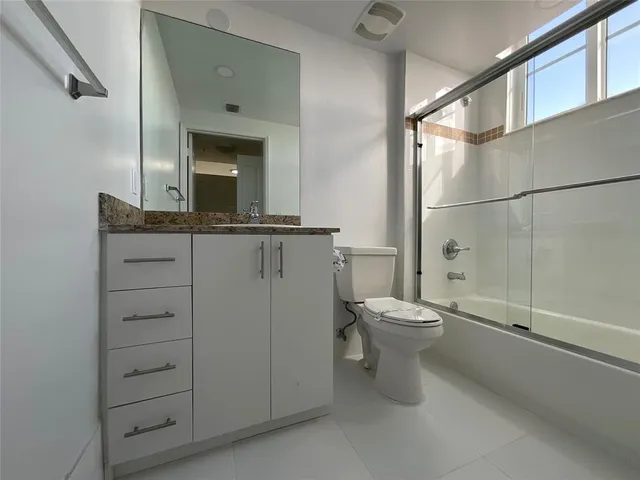 a bathroom with a granite countertop toilet a sink and a mirror