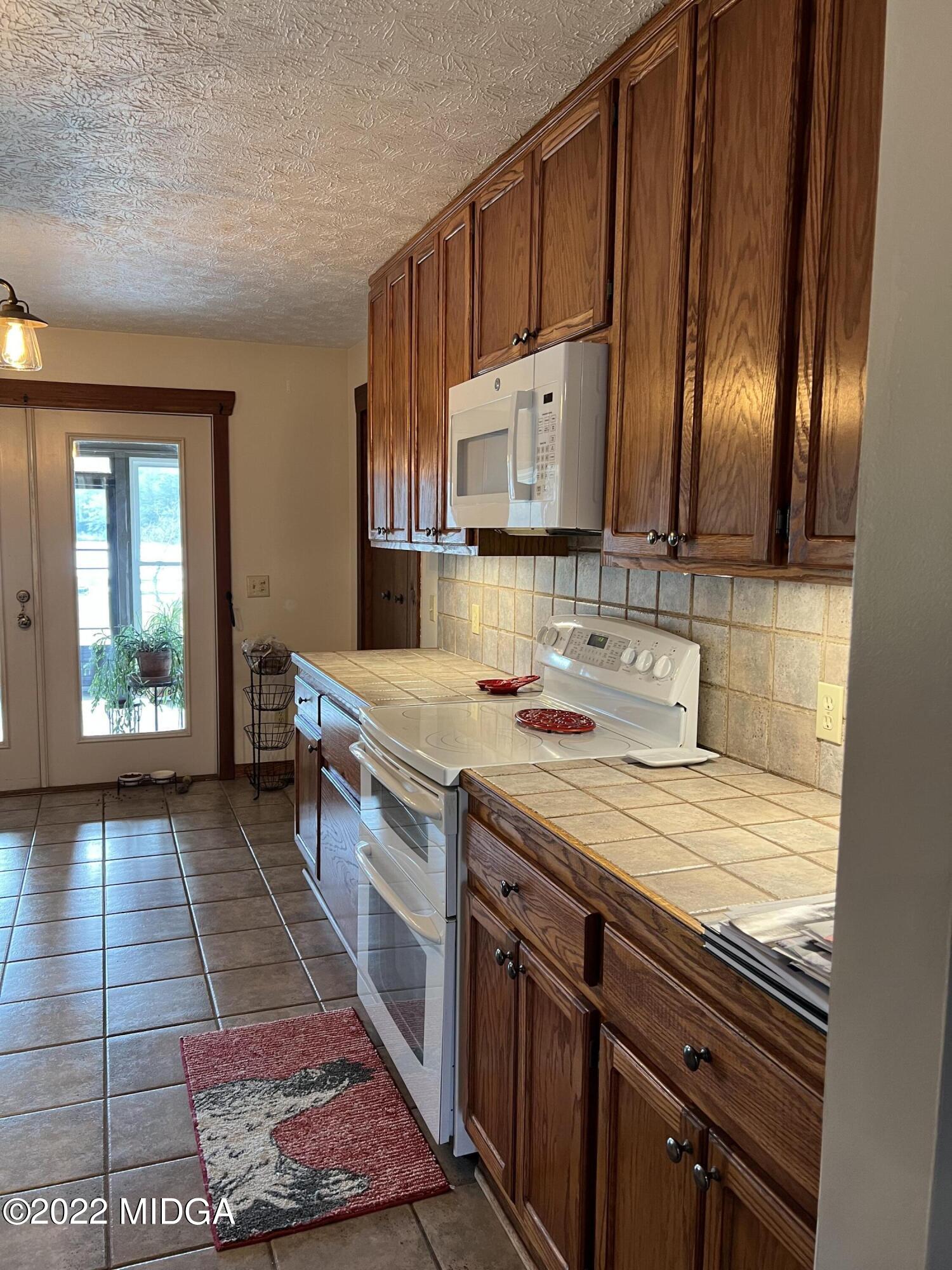 436 Barrow Road Reynolds, GA 31076 - Photo 20 of 91 a kitchen with kitchen island granite countertop a sink stove and cabinets