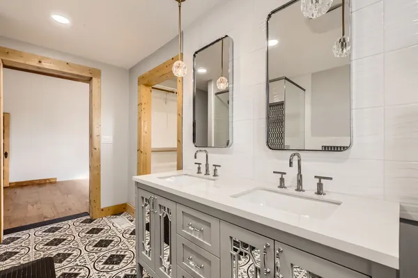 a bathroom with double vanity sink a mirror and a shower