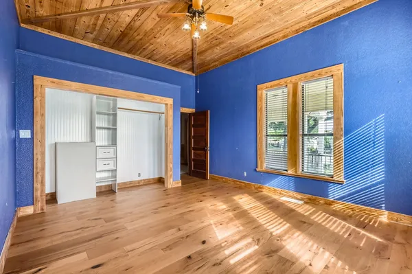 a view of an empty room with window and wooden floor