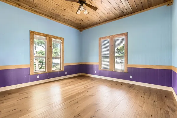 a view of empty room with wooden floor and fan