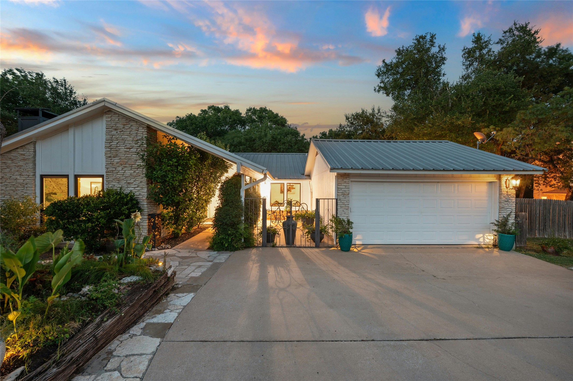 1503 Terrapin Court, Unit B Austin, TX 78746 - Photo 1 of 35 View of front of property featuring stone siding, driveway, a metal roof, and board and batten siding