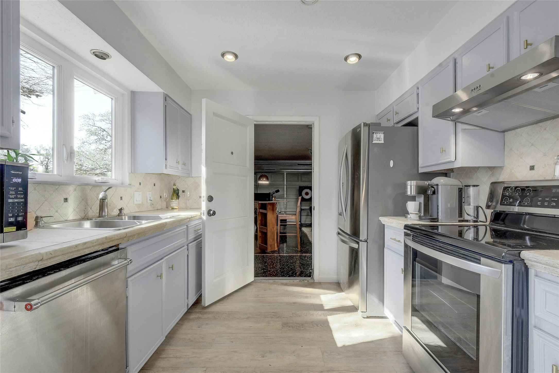 1503 Terrapin Court, Unit B Austin, TX 78746 - Photo 11 of 35 Kitchen featuring stainless steel appliances, decorative backsplash, under cabinet range hood, light countertops, and recessed lighting