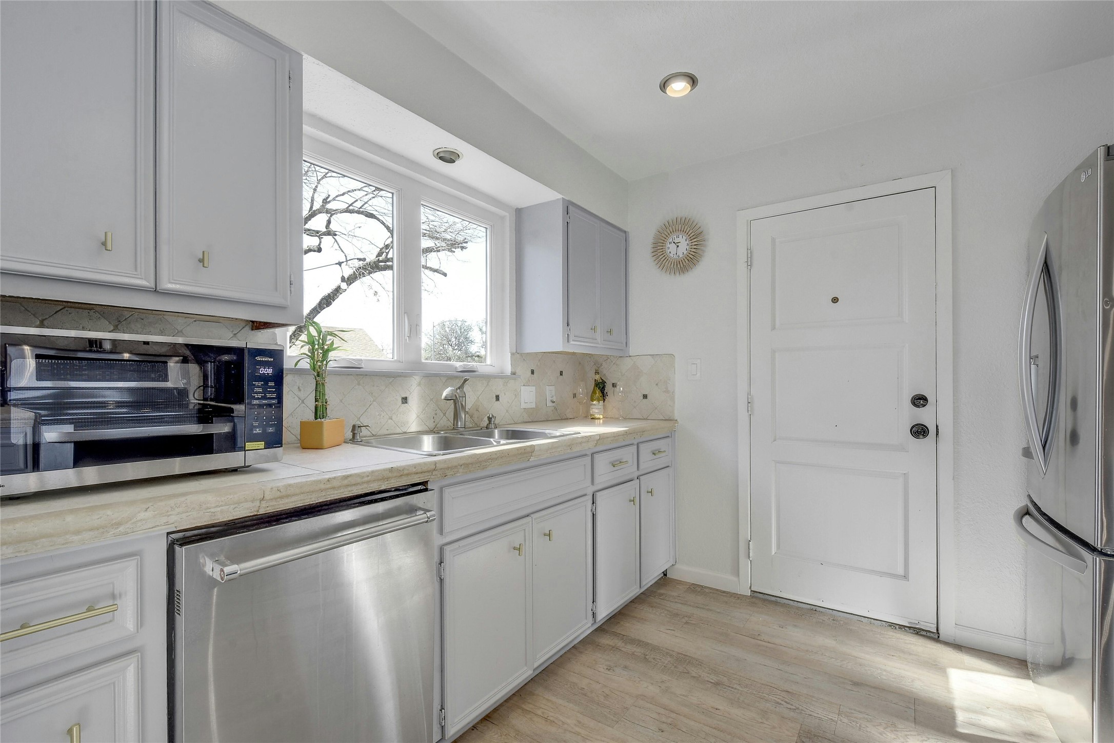 1503 Terrapin Court, Unit B Austin, TX 78746 - Photo 7 of 35 Kitchen featuring light countertops, appliances with stainless steel finishes, tasteful backsplash, and light wood-style floors