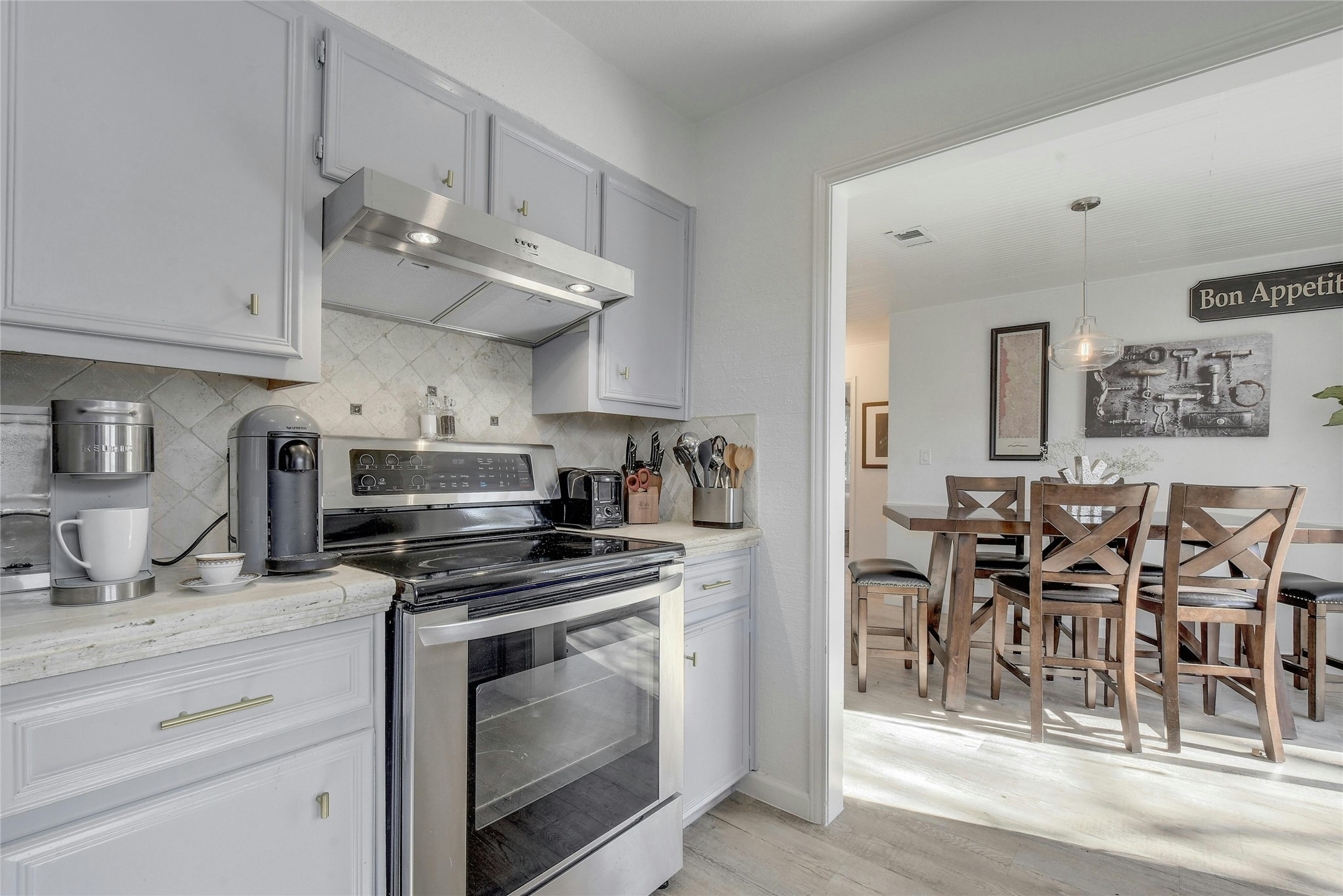 1503 Terrapin Court, Unit B Austin, TX 78746 - Photo 10 of 35 Kitchen featuring stainless steel electric range oven, under cabinet range hood, light wood finished floors, decorative backsplash, and decorative light fixtures