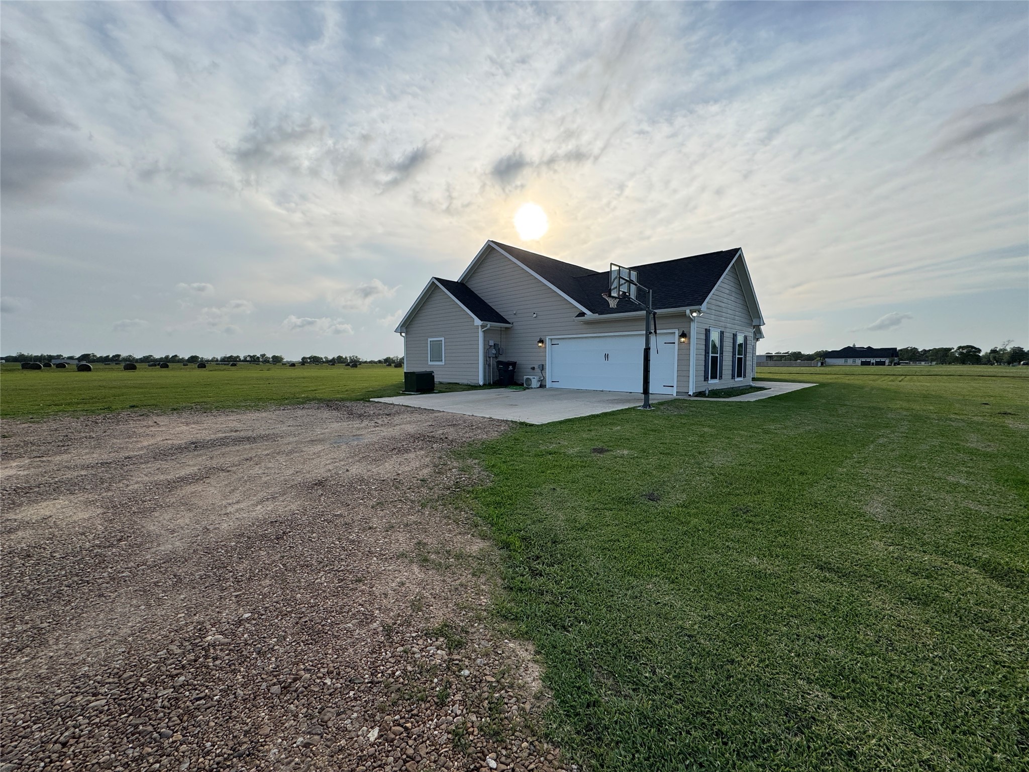 723 Sandy Corner Road El Campo, TX 77437 - Photo 2 of 20 This house is a modern, single-story home with a large attached garage, set on a spacious plot of land with expansive green fields. The setting offers a serene, rural atmosphere with plenty of open space.
