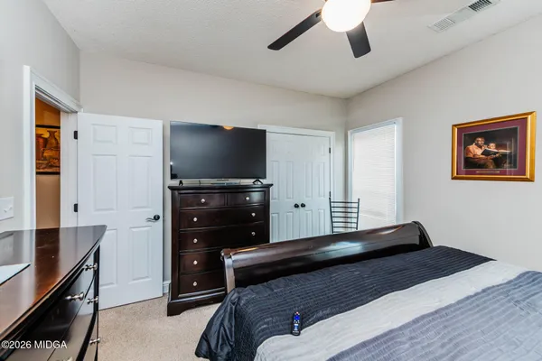 a bedroom with a bed and a flat tv screen on dresser