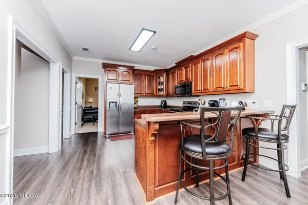 a kitchen with stainless steel appliances granite countertop a stove top oven a refrigerator a dining table and chairs with wooden floor