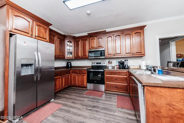 a kitchen with stainless steel appliances granite countertop a refrigerator stove top oven and a sink with large cabinets