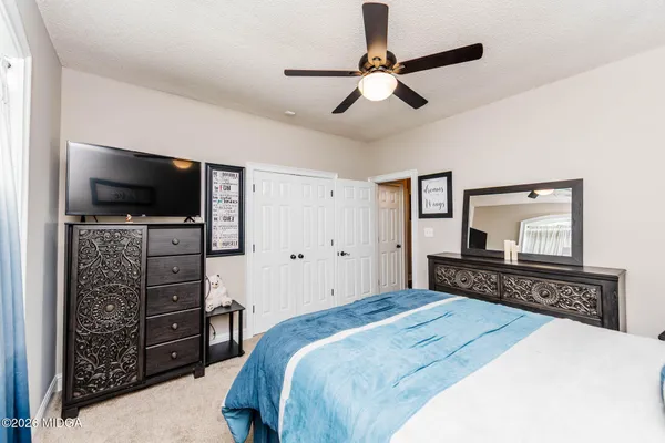a bedroom with a bed and a flat tv screen on dresser