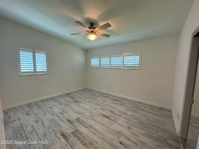 a view of an empty room with a window and wooden floor