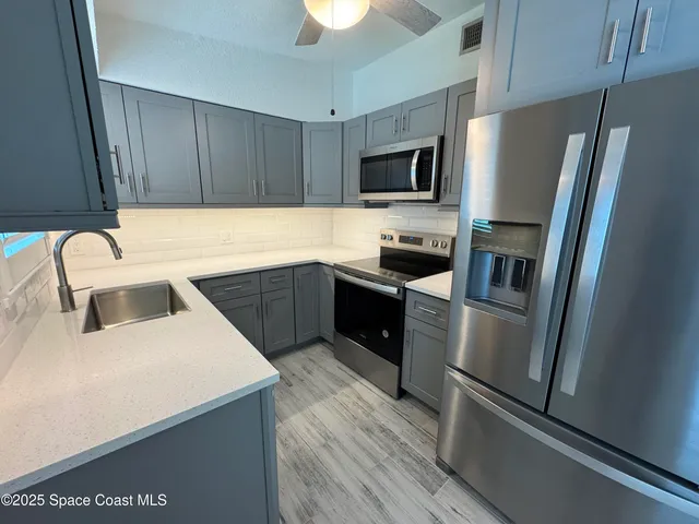 a kitchen with a sink a refrigerator a microwave and cabinets
