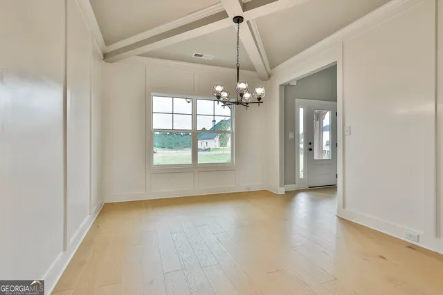 an empty room with chandelier fan and windows