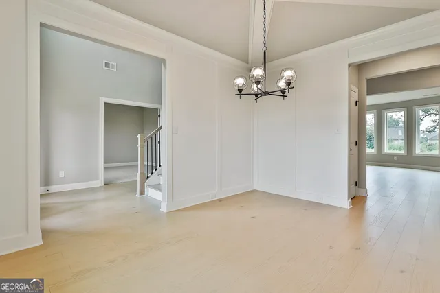 an empty room with chandelier fan and windows