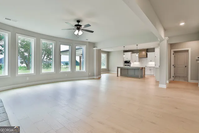 a view of an empty room with a window and wooden floor