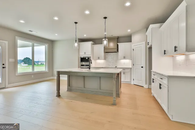 a large white kitchen with a large window and stainless steel appliances