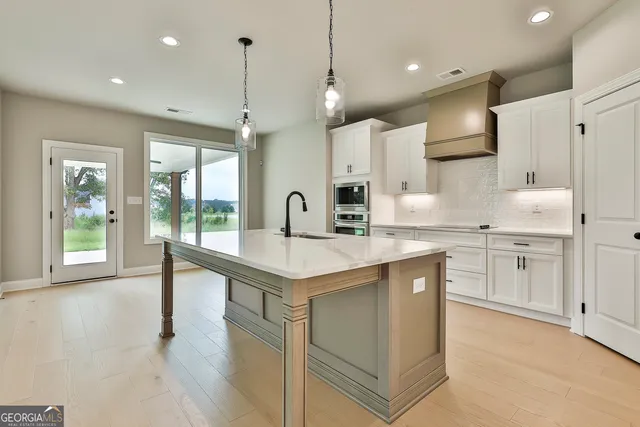 a kitchen with kitchen island a sink a stove a refrigerator and white cabinets with wooden floor