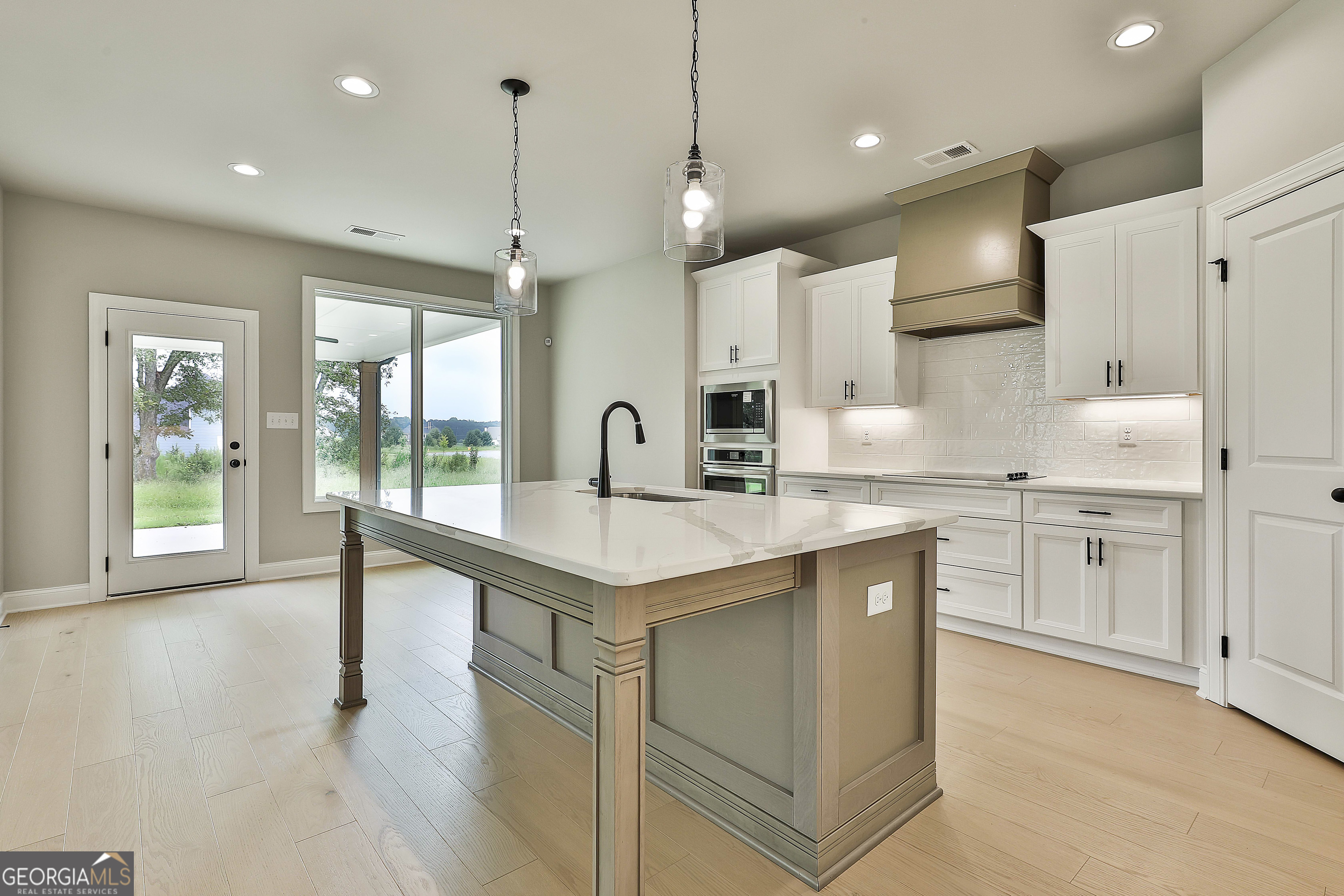 291 Grove Park, Unit 90 Senoia, GA 30276 - Photo 20 of 53 a kitchen with kitchen island a sink a stove a refrigerator and white cabinets with wooden floor