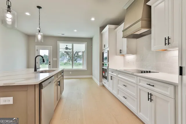 a kitchen with stainless steel appliances granite countertop a sink a stove and a wooden floors