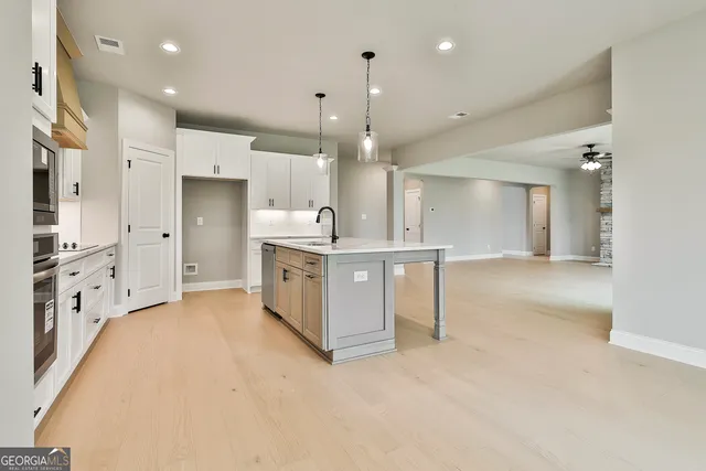 a large white kitchen with stainless steel appliances granite countertop a sink and cabinets