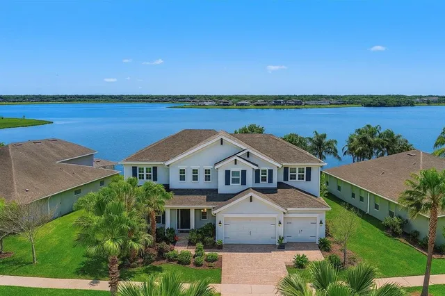 a front view of a house with a garden and lake view