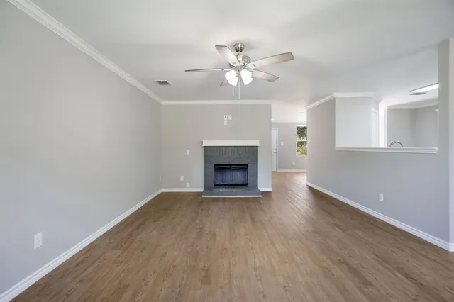 a view of an empty room with wooden floor and a fireplace