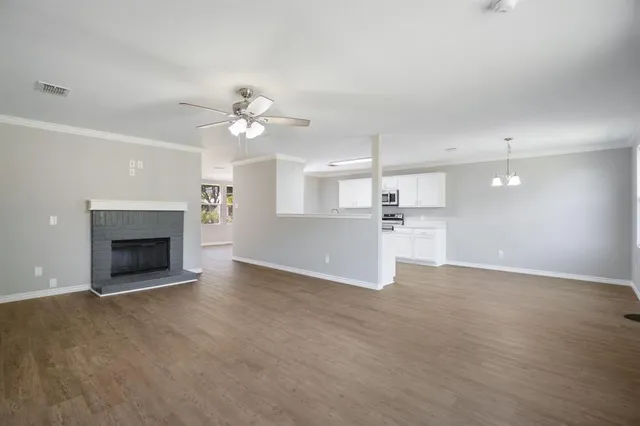 a view of a room a ceiling fan fireplace and a kitchen