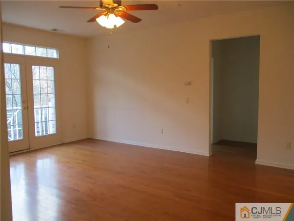 a view of an empty room with window and wooden floor
