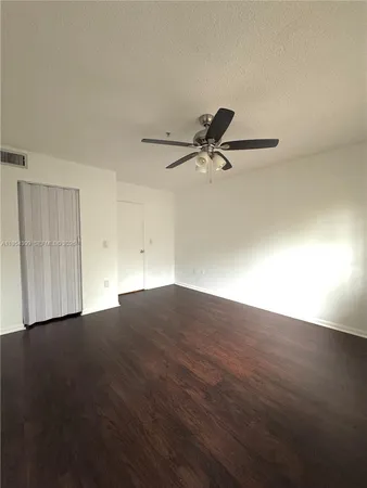 a view of a room with wooden floor and a ceiling fan