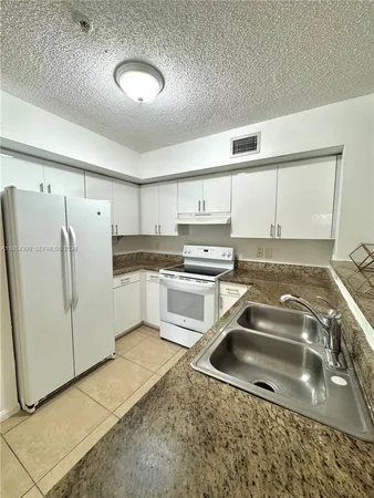 a kitchen with a refrigerator sink and cabinets