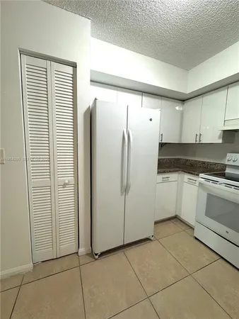 a kitchen with a refrigerator and white cabinets