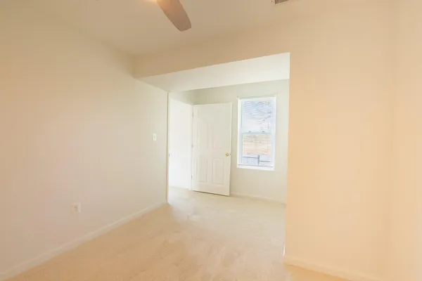 an empty room with windows and ceiling fan