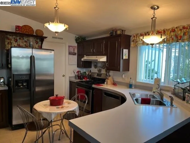 a kitchen that has a sink stainless steel appliances a table and chairs