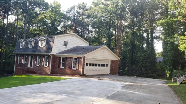 a view of a house with a yard and large trees