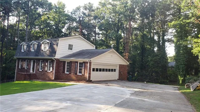 a view of a house with a yard and large trees