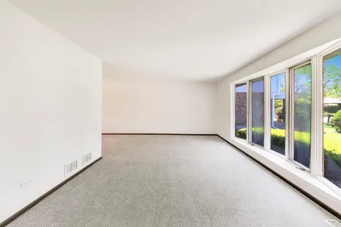 an empty room with floor to ceiling window and an outdoor view