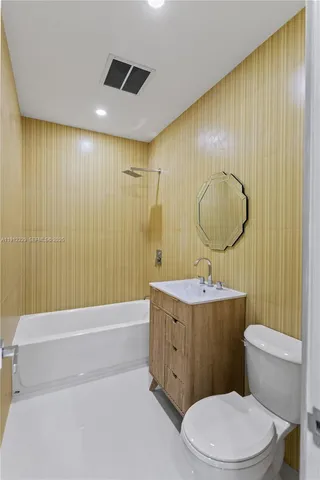 a bathroom with a granite countertop toilet a sink and a mirror