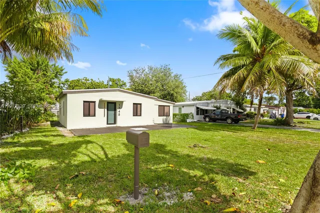 a backyard of a house with plants and palm trees