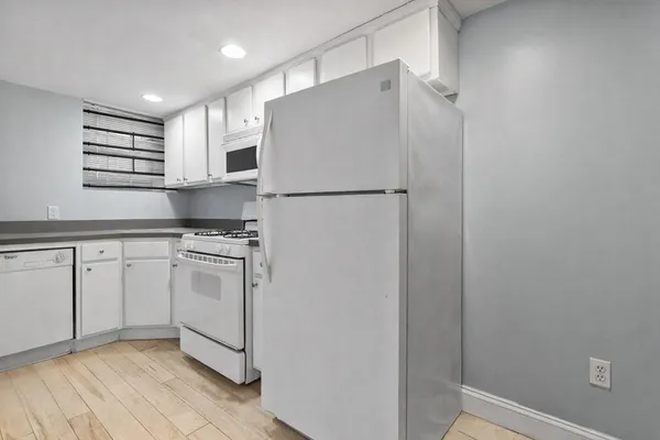 a kitchen with white cabinets and white appliances