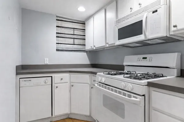a kitchen with white cabinets and appliances