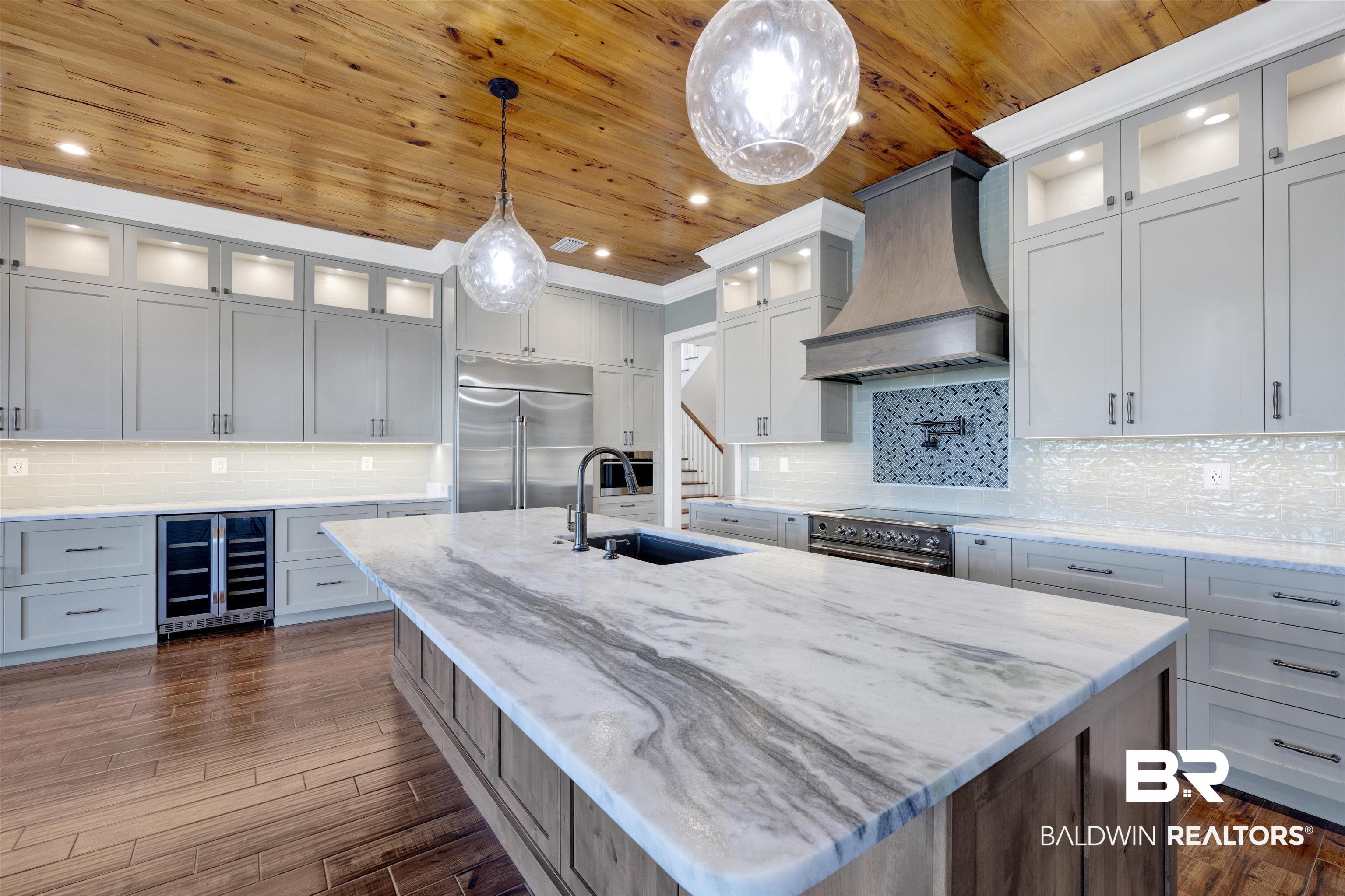 31729 River Road Orange Beach, AL 36561 - Photo 15 of 54 Kitchen with glass fronted cabinets, beverage cooler, pendant lighting, backsplash, and wood ceiling