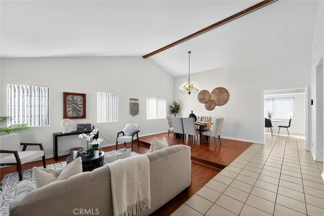a living room with couches and kitchen view with wooden floor