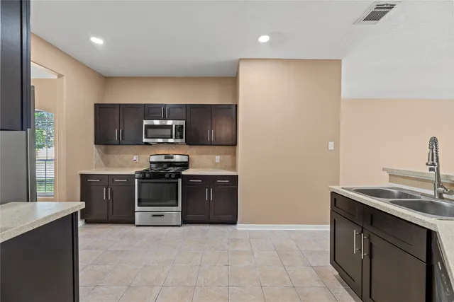 a large kitchen with stainless steel appliances granite countertop a stove a sink and a refrigerator