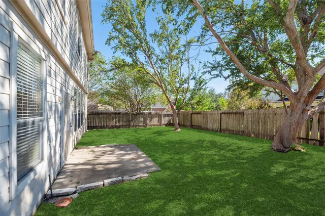 a view of a backyard with large trees and wooden fence