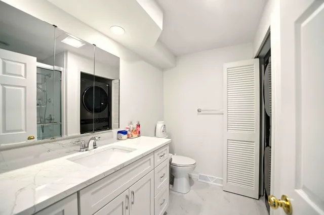 a bathroom with a granite countertop sink and a toilet