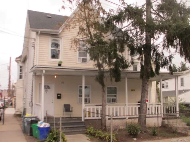 a front view of a house with a tree